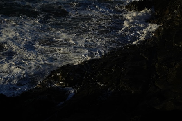 Photo les vagues et leur puissance frappent les falaises avec force révélant des formes merveilleuses au coucher du soleil