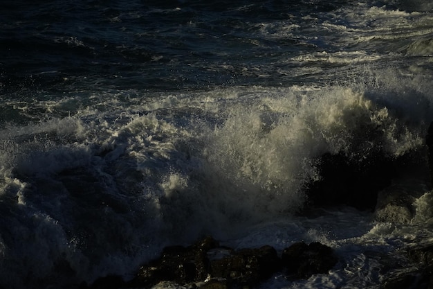 Photo les vagues et leur puissance frappent les falaises avec force révélant des formes merveilleuses au coucher du soleil