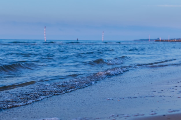 Photo vagues de la mer bleue sur la plage de sable du soir.