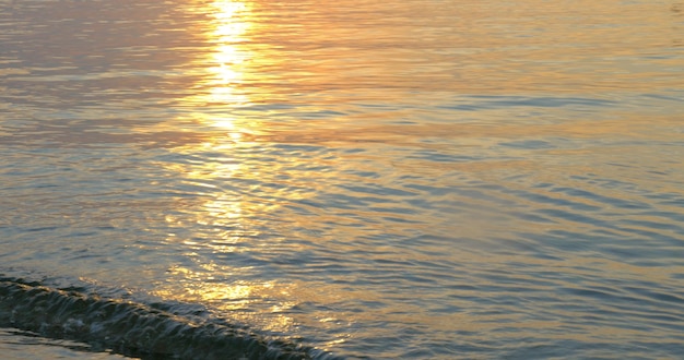 Vagues de la mer calme lavant le rivage au coucher du soleil