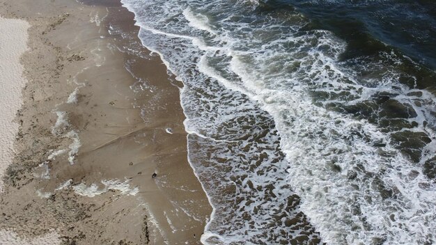 Vagues de la mer d'en haut Vagues de la mer avec de la mousse blanche roulant sur le bord de mer de la plage de sable