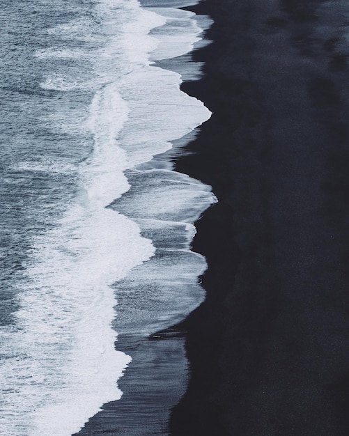 Les vagues de la mer s'écrasent sur une plage de sable noir en Islande