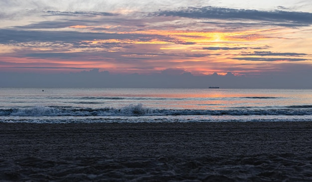 Vagues de la mer de texture au coucher du soleil avec des nuages roses