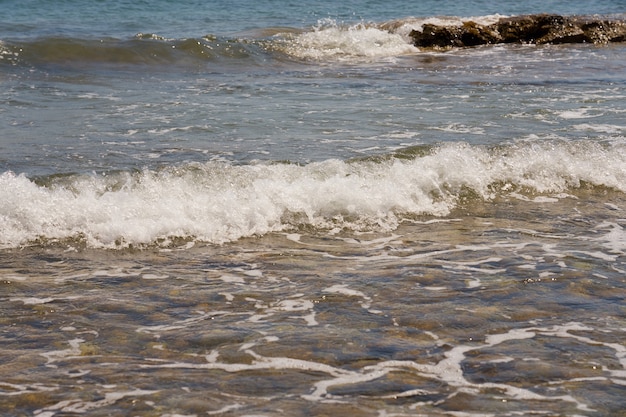 Vagues avec de la mousse sur la côte de la mer Égée en Crète, Grèce.