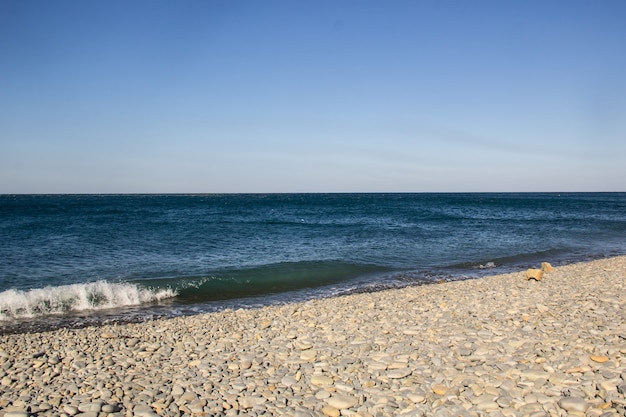 Les vagues mousseuses de la mer sur une plage de galets vide