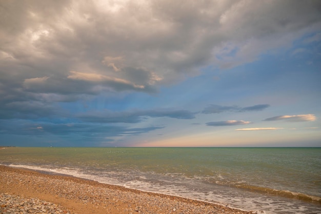 Vagues de l'océan roulant sur une plage sous d'énormes nuages blancs moelleux