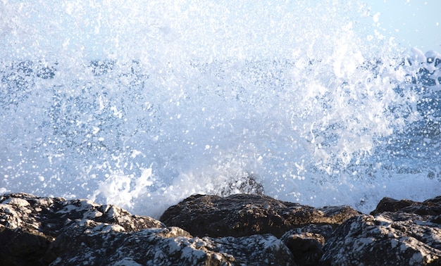 Les vagues ont éclaboussé les rochers par une journée très venteuse au coucher du soleil