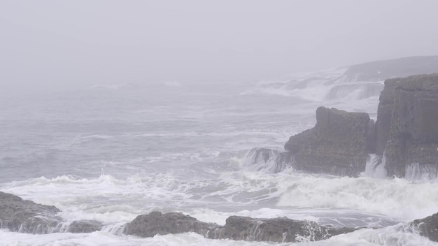 Vagues de paysage de mer brumeuse se brisant sur la plage de l'océan par temps brumeux orageux brumeux