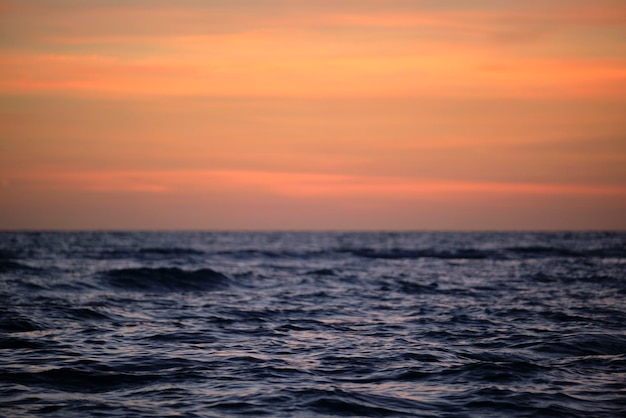 Vagues rouges spectaculaires de l'océan au coucher du soleil avec une douce eau sombre de la mer du soir