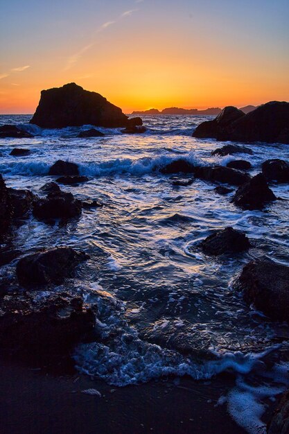 Les vagues s'écrasent autour des rochers sur l'océan pendant l'heure d'or