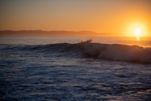 Vagues se brisant avec le lever du soleil en arrière-plan