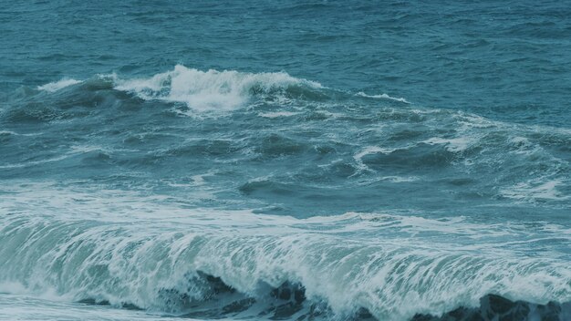 Les vagues se brisent sur la plage dangereuse les éclaboussures du vent les vagues la puissance des vagues s'éclatent