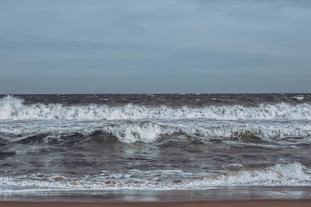 Les vagues de la tempête océanique s'écrasent de façon spectaculaire sur les éclaboussures Ligne d'horizon du ciel Bord de l'eau de mer nature vue de face conception de papier peint marin Mauvais temps nuageux couvert vert foncé ton bleu turquoise pâle mat