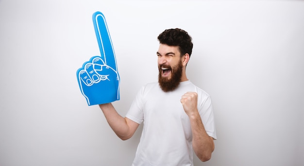 Vainqueur homme barbu avec un doigt de mousse bleu hurlant de bonheur.