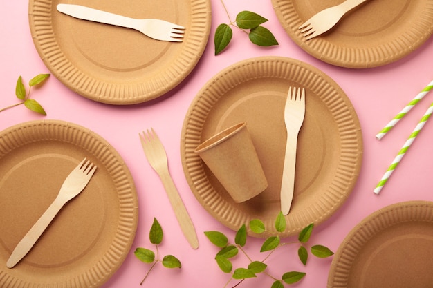 Vaisselle jetable écologique avec des feuilles vertes sur fond rose. Zéro déchet, écologique, fond sans plastique. Photo verticale