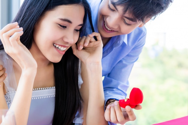 Valentin et asiatique Jeune concept de couple doux heureux, asiatique un homme avec une bague de fiançailles faisant une proposition de mariage à une femme après le déjeuner dans un restaurant, des plans de mariage pour les mariés