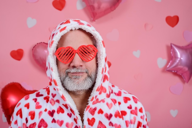 Valentine39s Day portrait d'un homme aux cheveux gris portant des lunettes en forme de coeur et un peignoir avec des coeurs rouges