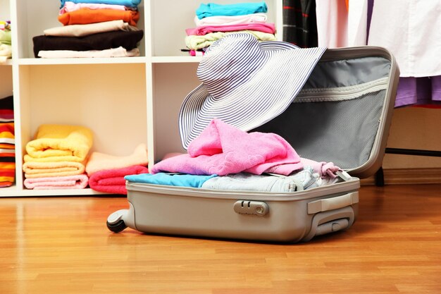 Valise argentée ouverte avec des vêtements dans la chambre