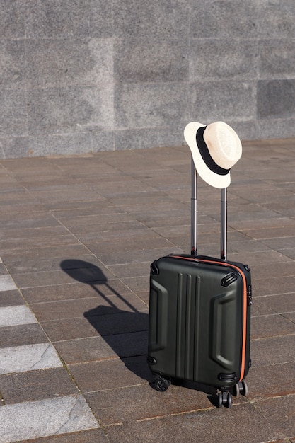 Valise avec un chapeau de paille sur fond gris