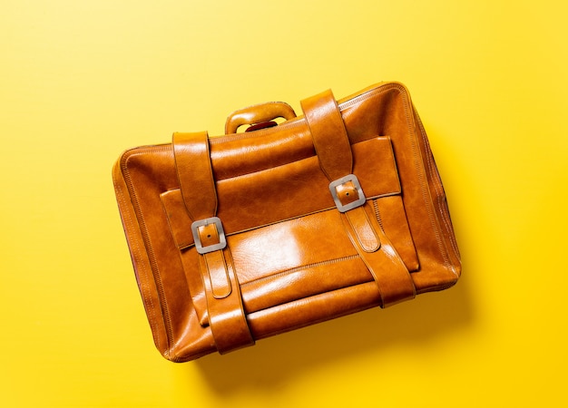 Valise en cuir marron sur un espace jaune