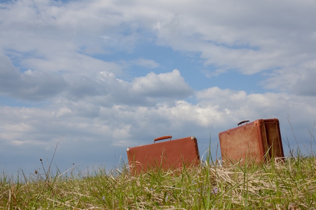 Valise deux route marron assis sur l&#39;herbe contre le ciel bleu