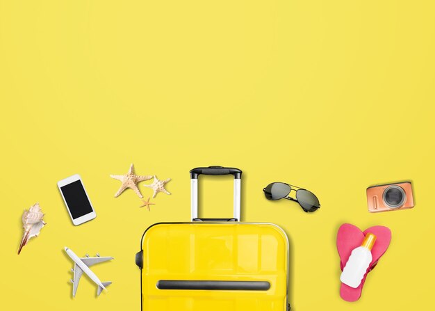 Valise jaune avec accessoires de voyage sur fond jaune. concept de voyage