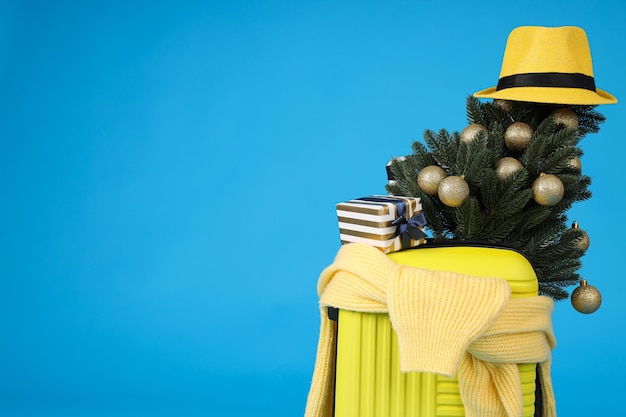 Une valise jaune avec un arbre de Noël décoré et un chapeau