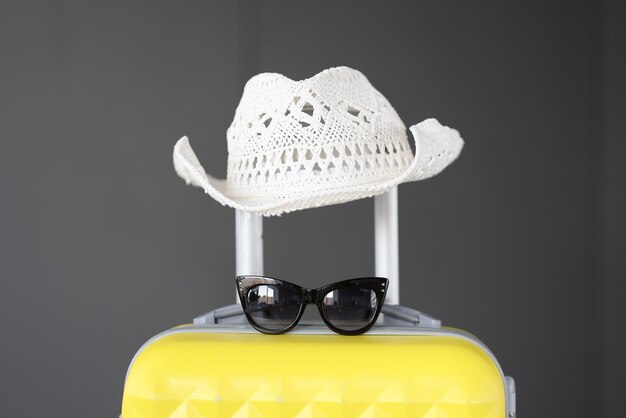 Valise jaune avec chapeau panama blanc et lunettes de soleil. Concept de tourisme et de voyage