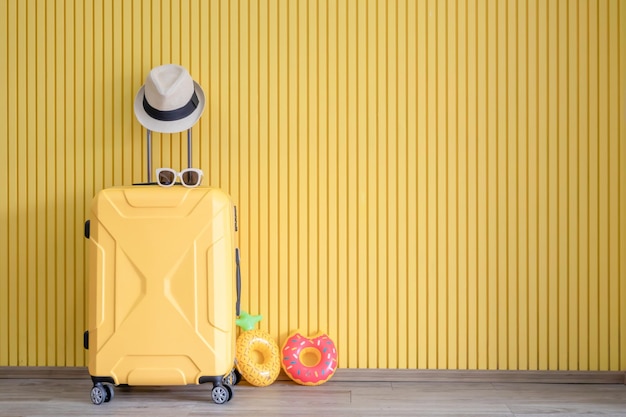 Valise jaune et avec équipement de voyageur sur fond jaune Concept de voyage d'été