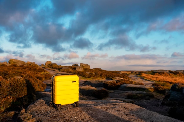 Valise jaune avec foulard orange en haut de la montagne contre le ciel bleu au lever du soleil Travel concept