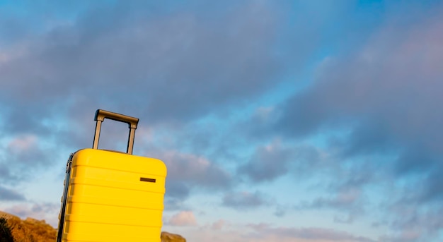 Valise jaune avec foulard orange en haut de la montagne contre le ciel bleu au lever du soleil Travel concept