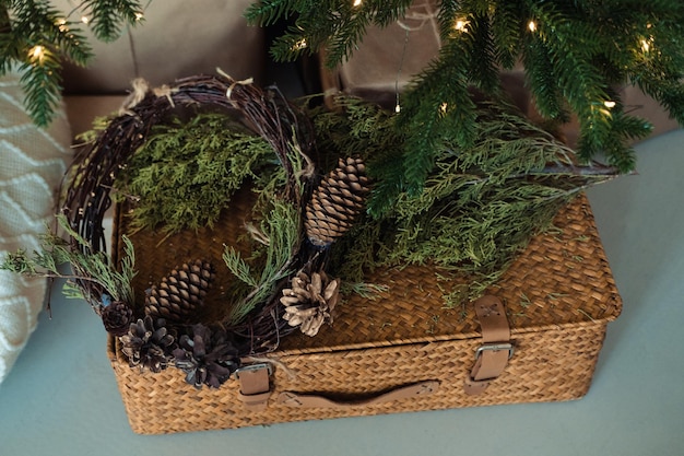 Valise en osier décorée de branches d'épicéa et d'un cône de décoration de Noël