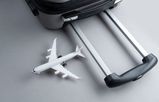 Valise plate gris avec mini avion sur gris