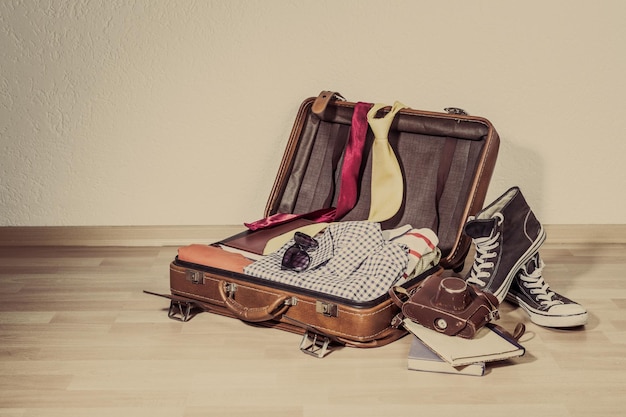 Photo valise rétro avec objets de voyage sur planche de bois