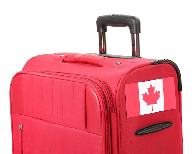 Valise rouge avec autocollant avec drapeau du Canada isolé sur blanc