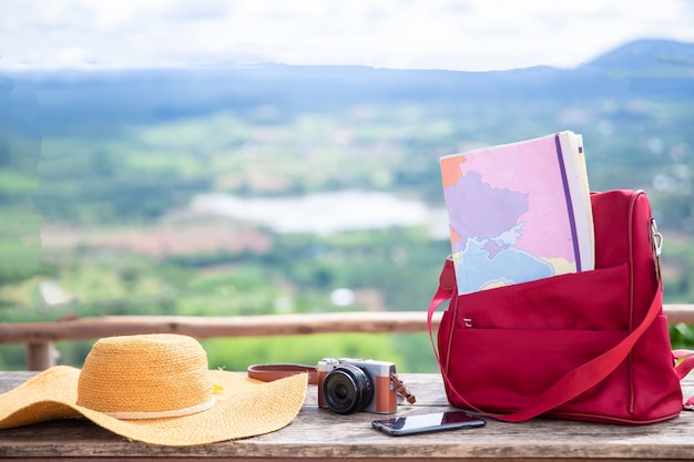 Valise vintage, chapeau hipster, appareil photo et passeport sur une terrasse en bois.