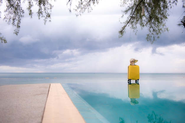 Valise de voyage avec chapeau sur la plage