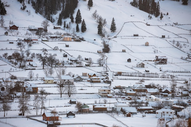 vallée rurale des carpates en hiver. magnifique paysage de montagne avec village par une journée ensoleillée.
