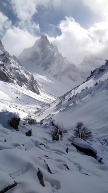 Une vallée tranquille se trouve sous un sommet de montagne spectaculaire avec de la neige couvrant le paysage et une végétation clairsemée regardant à travers les nuages jetant une lumière douce sur la scène