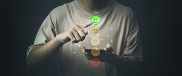 Évaluation et satisfaction du service client Main d'homme touchant une bonne note de sourire avec smartphone Concept d'enquête de rétroaction