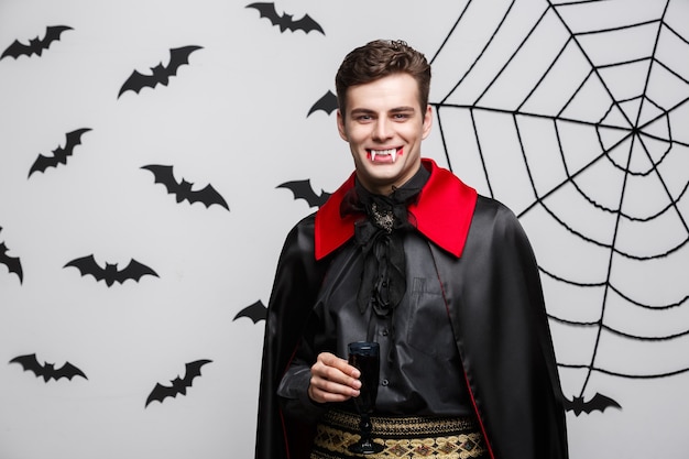 Vampire Halloween Concept - Portrait de beau vampire caucasien aime boire du vin rouge sanglant.