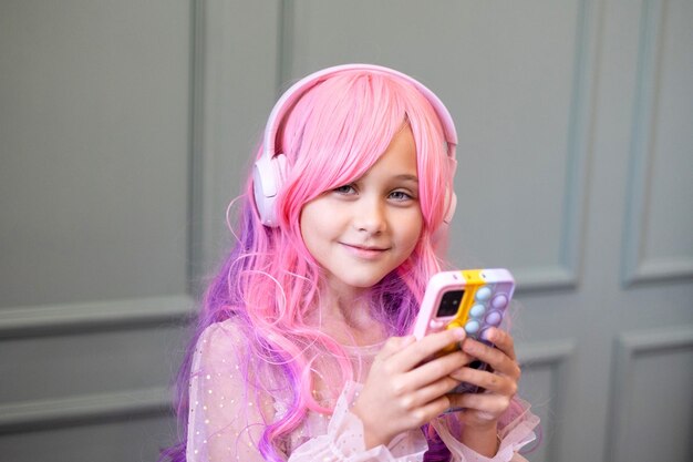 Vanilla Girl Kawaii vibes Petite fille aux cheveux roses fait une fête en style barbie Écoute de la musique avec des écouteurs téléphone portable