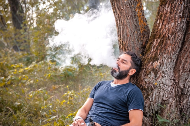 Photo vaper barbu fumant une cigarette électronique en plein air