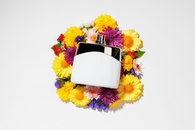 Vaporisateur de parfum et petites fleurs sur mur gris se bouchent