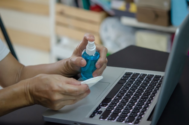 Vaporiser de l'alcool pour nettoyer l'ordinateur et essuyer les germes. Concept de soins de santé.