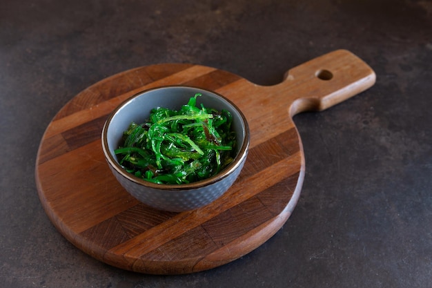 Varech de mer dans le bol sur une planche de cuisine en bois