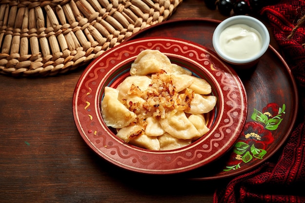 Varenyky ukrainien traditionnel farci de pommes de terre et d'oignons frits dans des plats d'argile Cuisine ukrainienne Gros plan