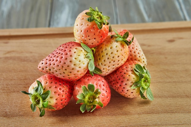 Variété d'ananas de fraises fraîches sélectionnées empilées dans la diapositive sur fond de bois