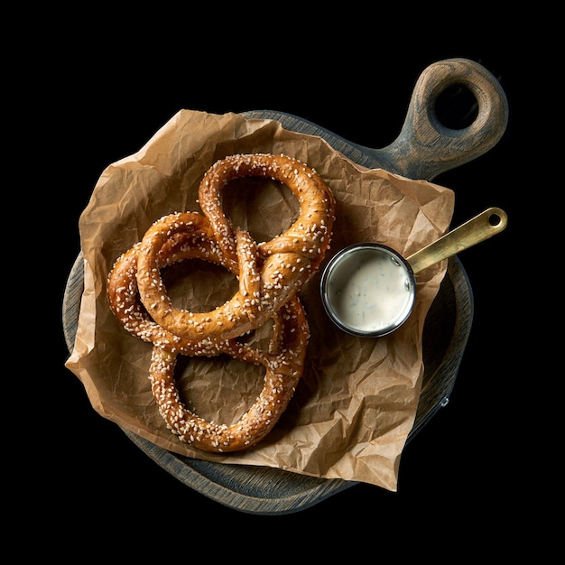 Variété de bagels faits maison aux graines de sésame, fromage à la crème, sauce pesto, œufs, radis, herbes servis sur papier froissé avec des ingrédients ci-dessus sur fond de texture bleue.