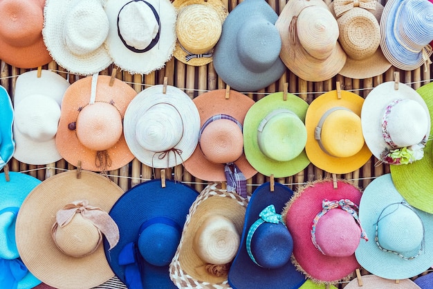 Photo une variété de chapeaux à la mode et colorés accrochés sur le fond de bambou du magasin du trottoir